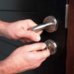 Man hand opening black door with key close up